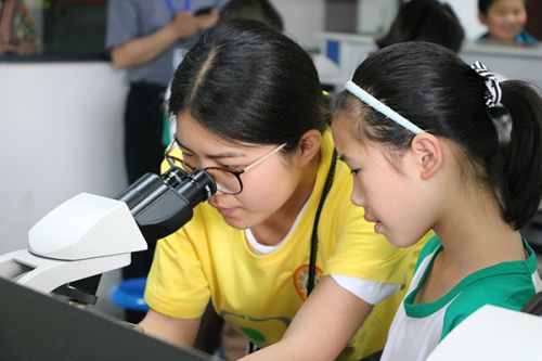 志愿者在协助小朋友使用显微镜